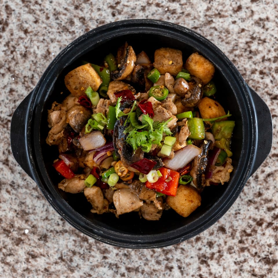 Sizzling dish with mushrooms, peppers, and onions.