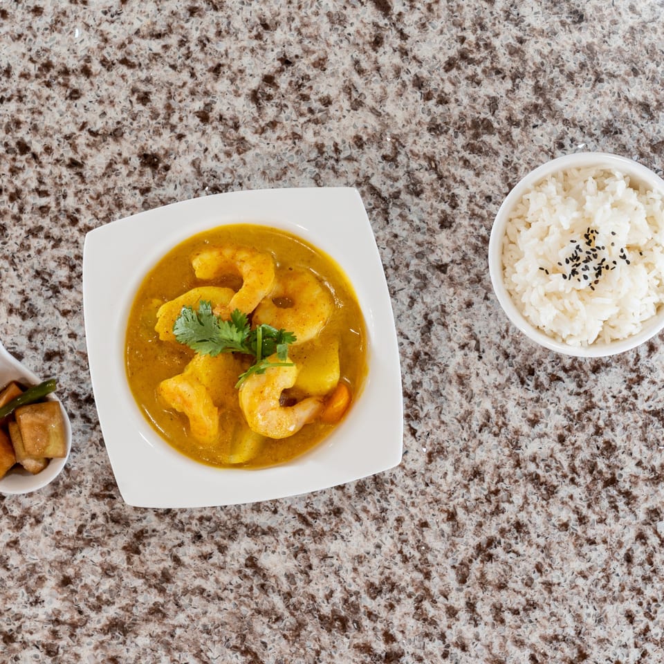 Shrimp curry served with rice and pickled vegetables.