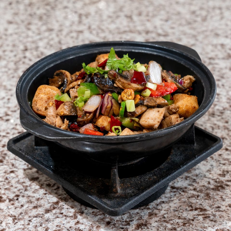 Sizzling dish with mushrooms, peppers, and onions.